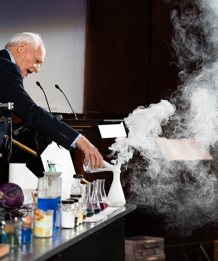 Science lecturer performing a live chemistry experiment during a STEM lecture at the London International Youth Science Forum